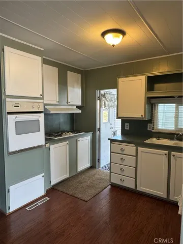 a kitchen with granite countertop white cabinets and white appliances