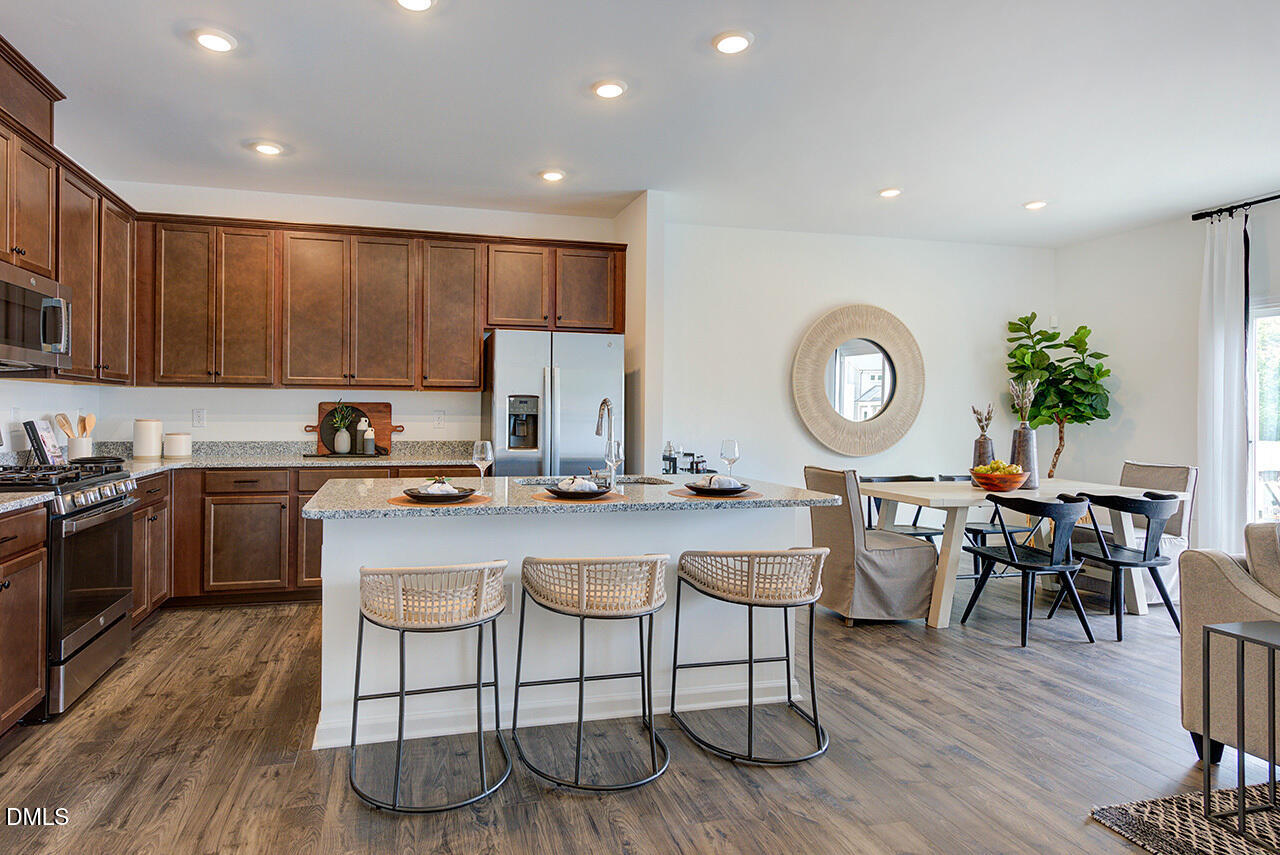 45 Shay Street Angier, NC 27501 - Photo 6 of 32 a kitchen with stainless steel appliances granite countertop a stove top oven a sink a dining table and chairs with wooden floor