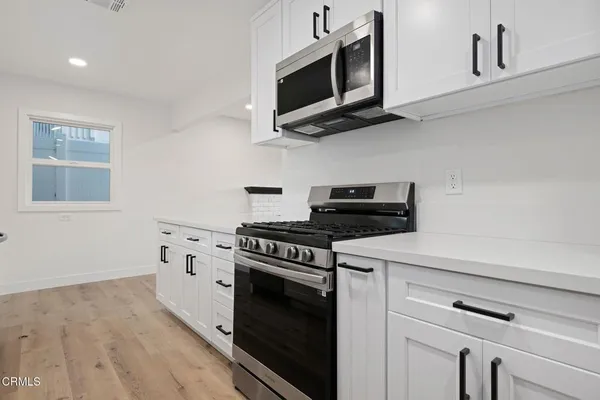 a kitchen with stainless steel appliances white cabinets and a stove top oven