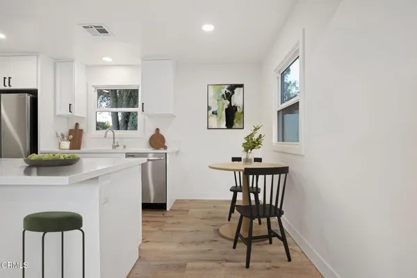 a kitchen with stainless steel appliances a dining table chairs and a refrigerator