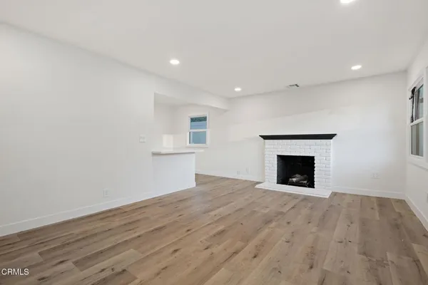 a view of empty room with wooden floor and fireplace