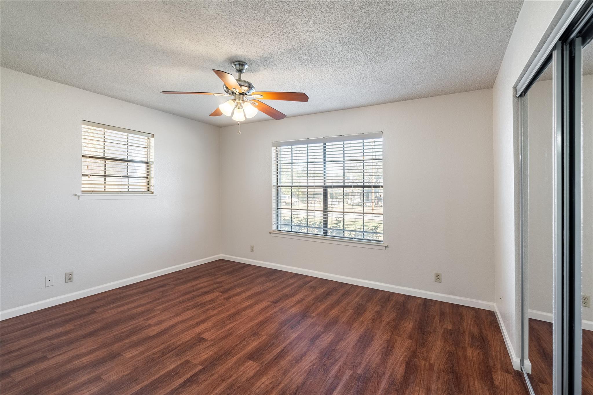3800 Foust Trail, Unit B Georgetown, TX 78628 - Photo 12 of 16 Rich wood flooring grounds this airy bedroom, featuring natural light from two windows and a convenient ceiling fan.