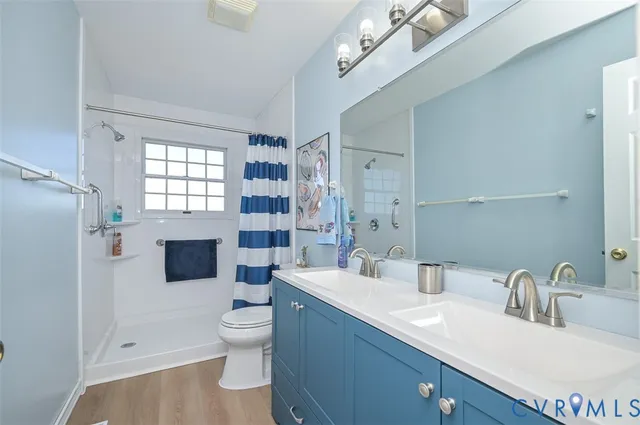 a bathroom with a double vanity sink toilet mirror and shower