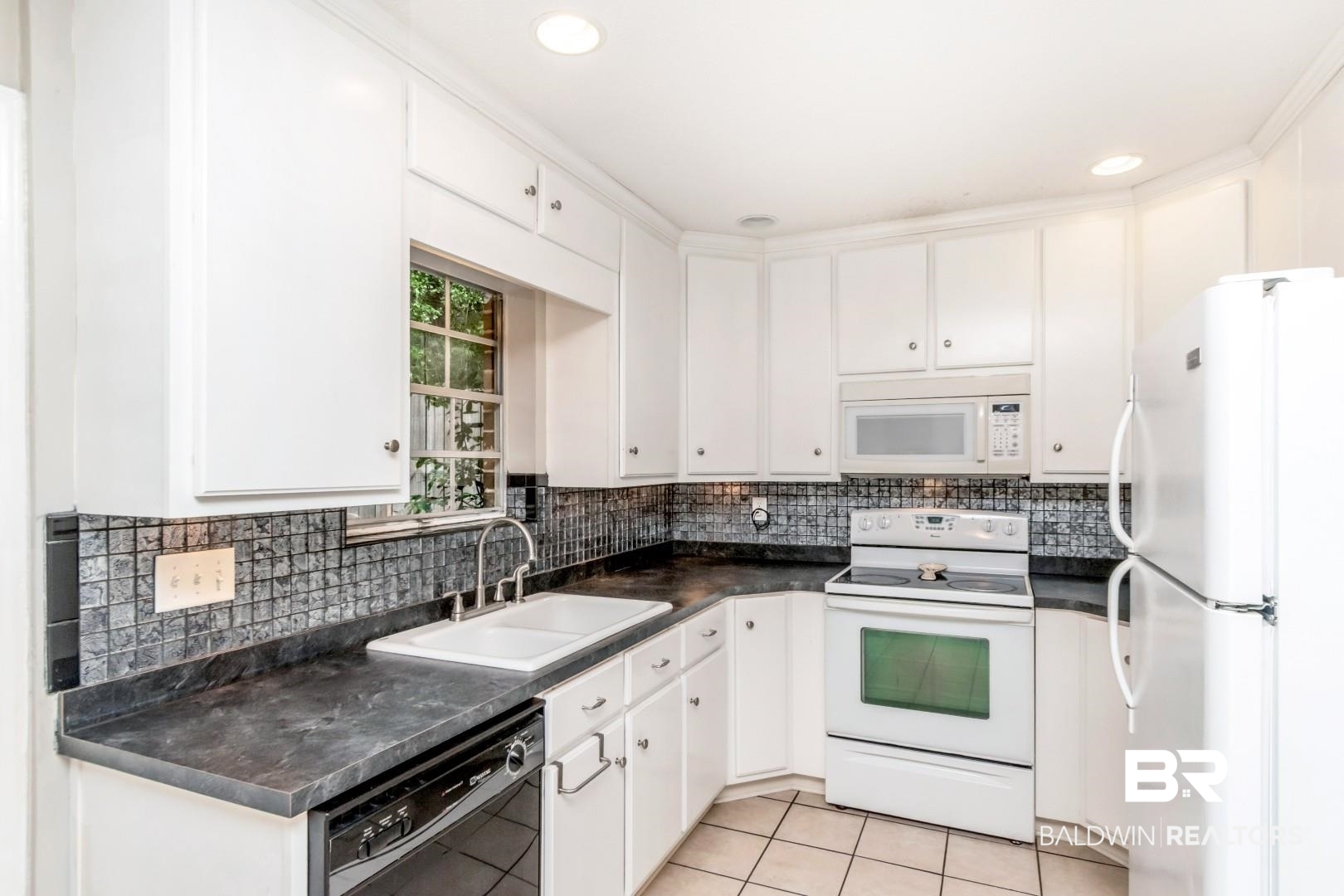 118 Du Rhu Drive, Unit H Mobile, AL 36608 - Photo 8 of 19 Kitchen featuring white cabinetry, dark stone-finish countertops, and a mosaic tile backsplash