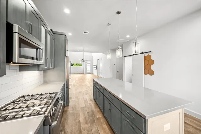 a large kitchen with stainless steel appliances granite countertop a sink a stove and a refrigerator