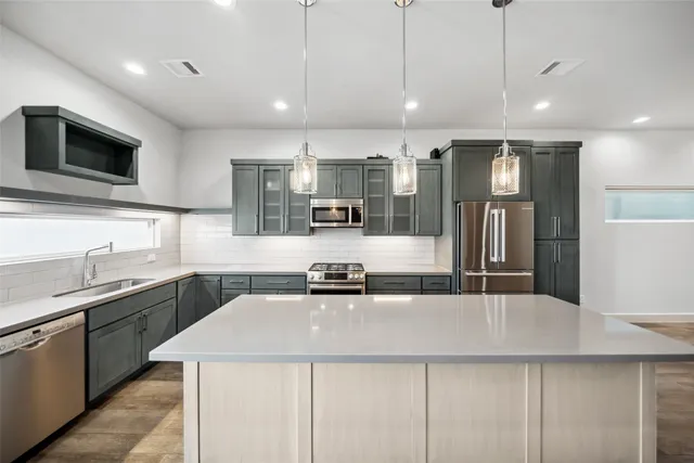 a kitchen with stainless steel appliances granite countertop a sink a stove and a refrigerator