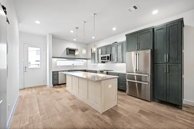 a large kitchen with stainless steel appliances kitchen island granite countertop a refrigerator and a stove top oven