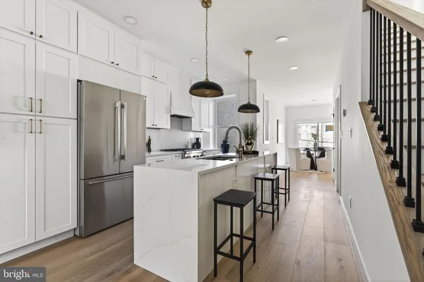a kitchen with stainless steel appliances kitchen island a dining table chairs and a wooden floor