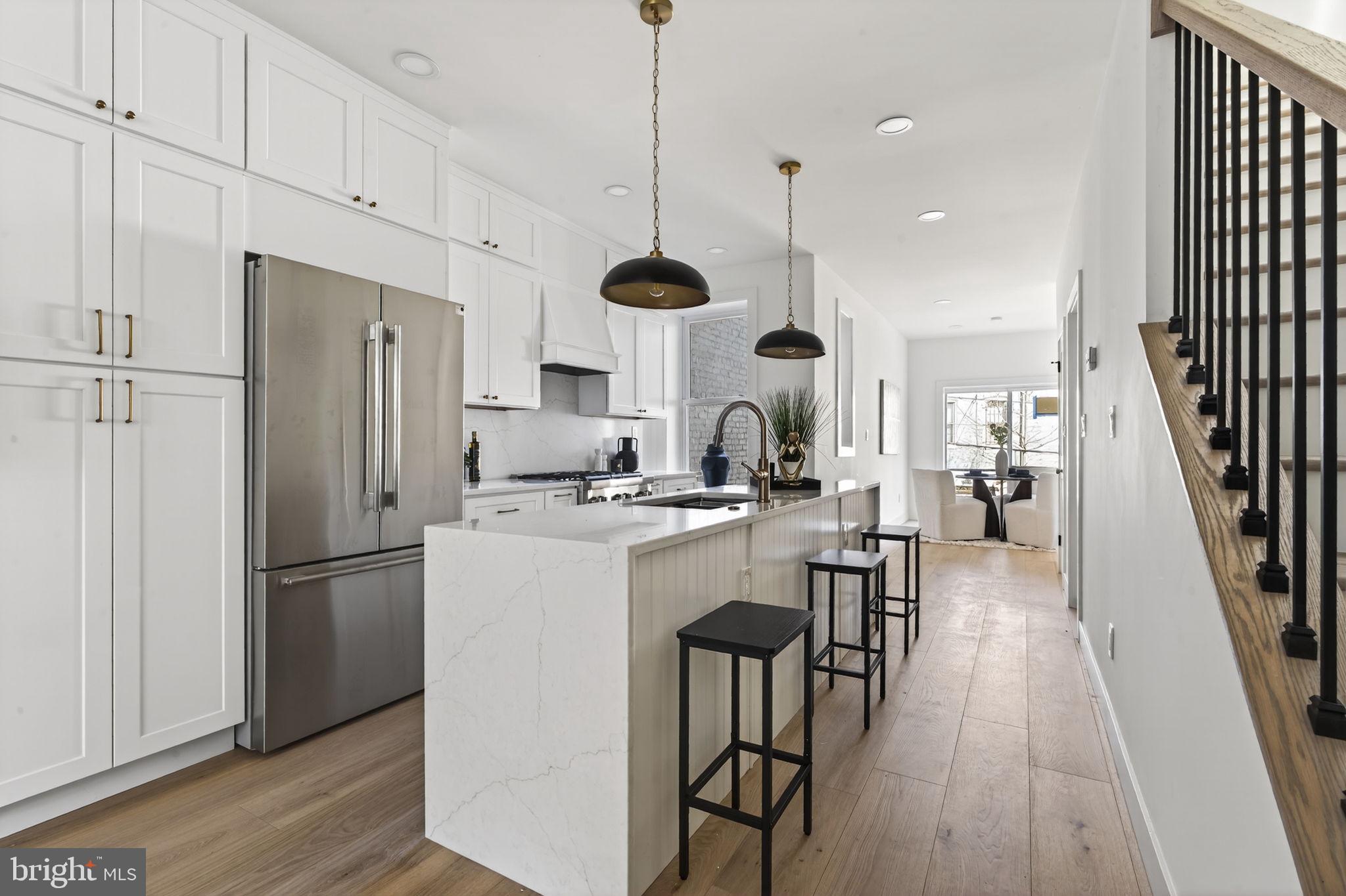 a kitchen with stainless steel appliances kitchen island a dining table chairs and a wooden floor