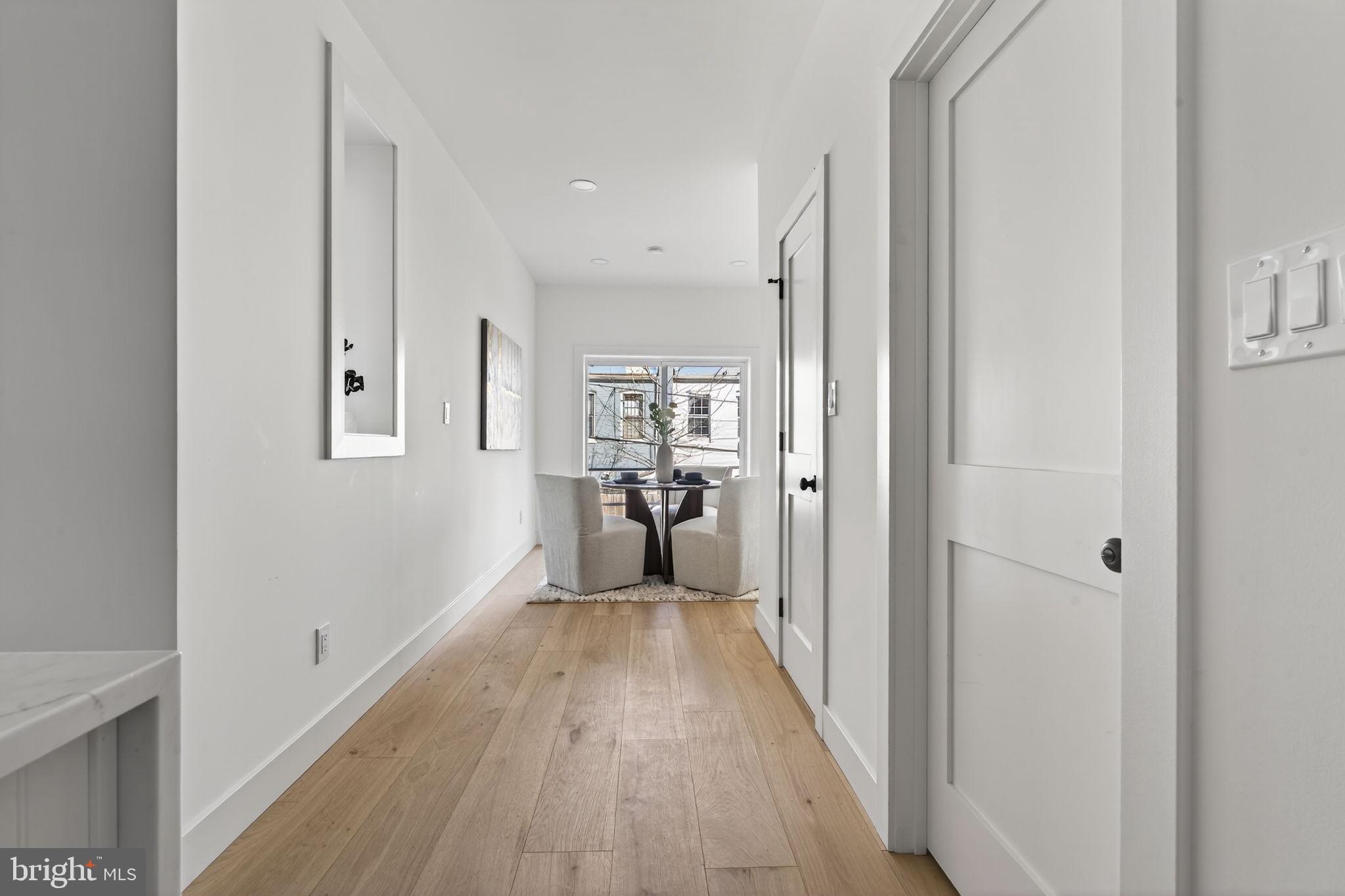 609 Harvard Street Northwest Washington, DC 20001 - Photo 13 of 41 a view of a hallway with wooden floor a kitchen space with a refrigerator and windows