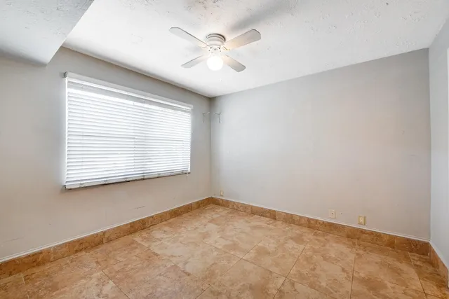 an empty room with chandelier fan and windows