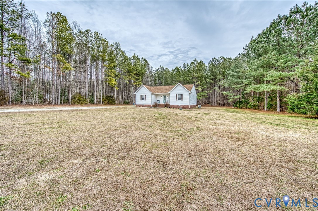 7045 Tranquility Lane Sutherland, VA 23885 - Photo 2 of 27 a view of white house with a big yard and large trees