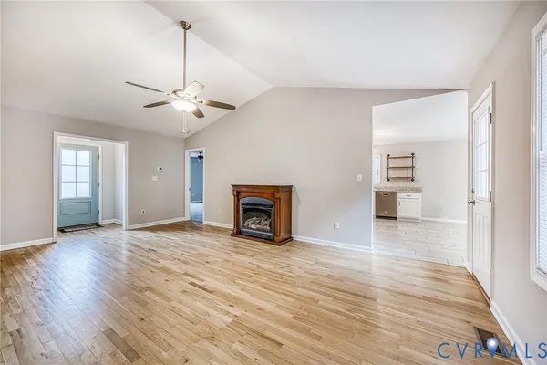 a view of an empty room with window and wooden floor