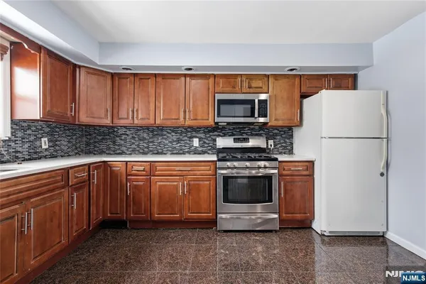a kitchen with stainless steel appliances granite countertop a refrigerator a stove a sink and a microwave