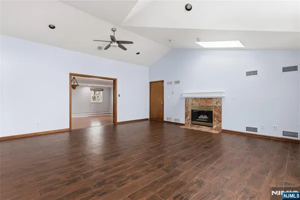 an empty room with wooden floor fireplace and windows