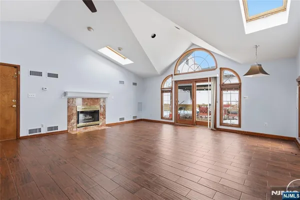 a view of an empty room with wooden floor fireplace and a window