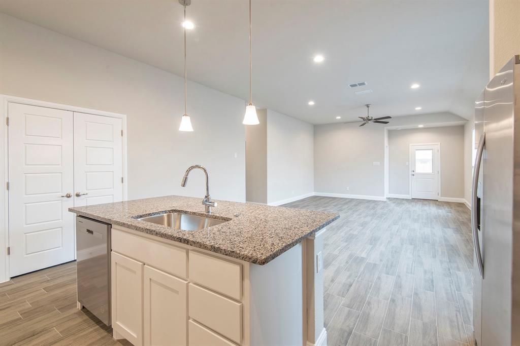 2301 Ruff Road Denton, TX 76205 - Photo 9 of 23 Kitchen island featuring a stainless steel sink, gooseneck faucet, light-toned granite countertop, and white cabinetry