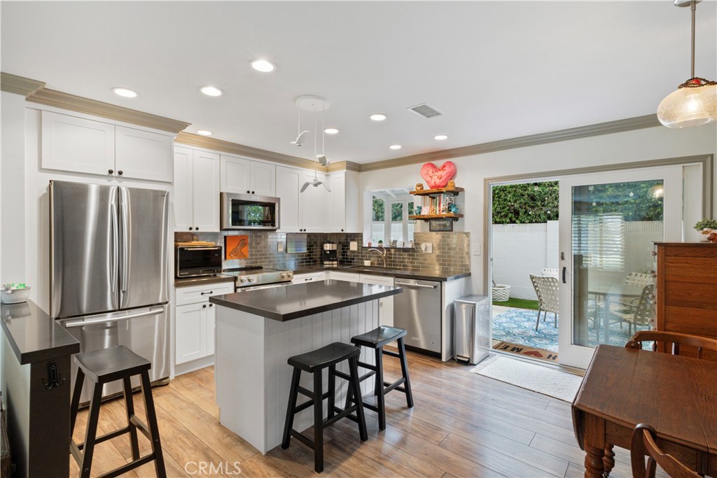 419 Gloucester Drive Costa Mesa, CA 92627 - Photo 7 of 51 a kitchen with stainless steel appliances granite countertop a refrigerator a stove a sink a dining table and chairs with wooden floor