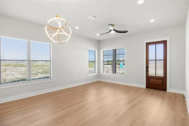 an empty room with wooden floor and windows