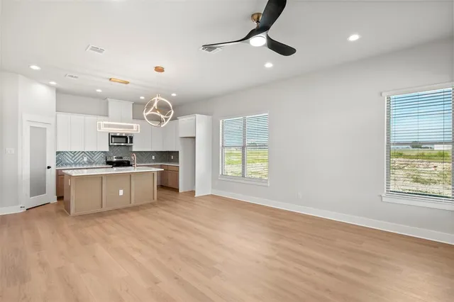 a large kitchen with kitchen island granite countertop a stove a sink dishwasher and white cabinets with wooden floor