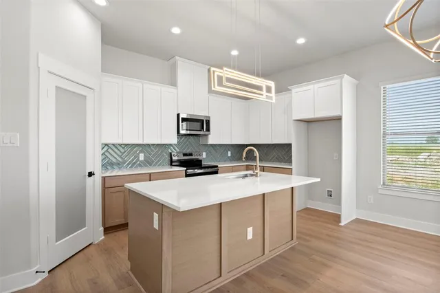 a kitchen with a sink a stove a refrigerator cabinets and a window