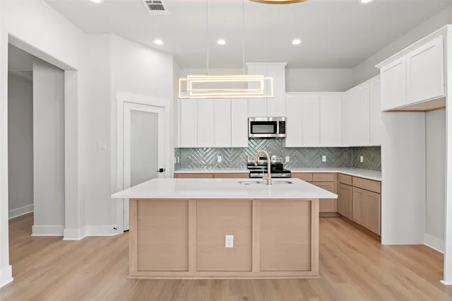 a kitchen with kitchen island a sink stainless steel appliances and cabinets