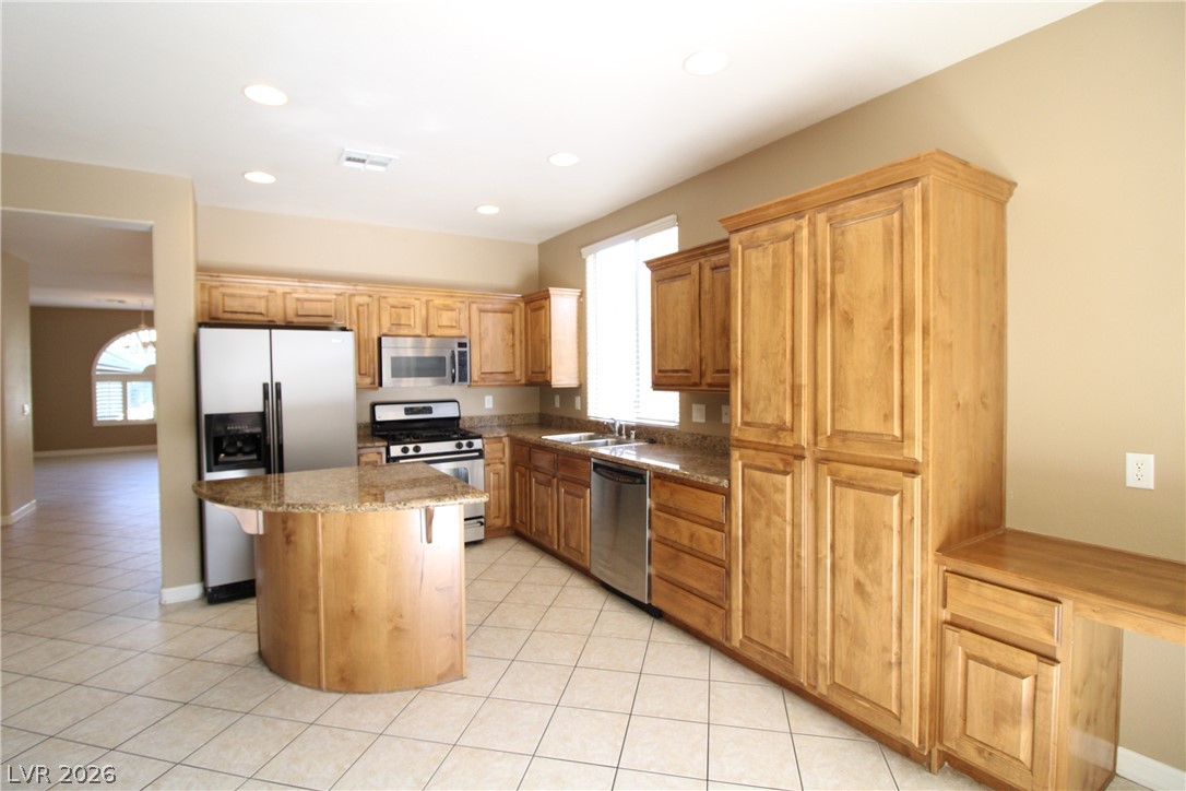 754 Rise Canyon Drive Henderson, NV 89052 - Photo 8 of 34 Culinary adventures await in this kitchen featuring abundant wood cabinetry and stone countertops.