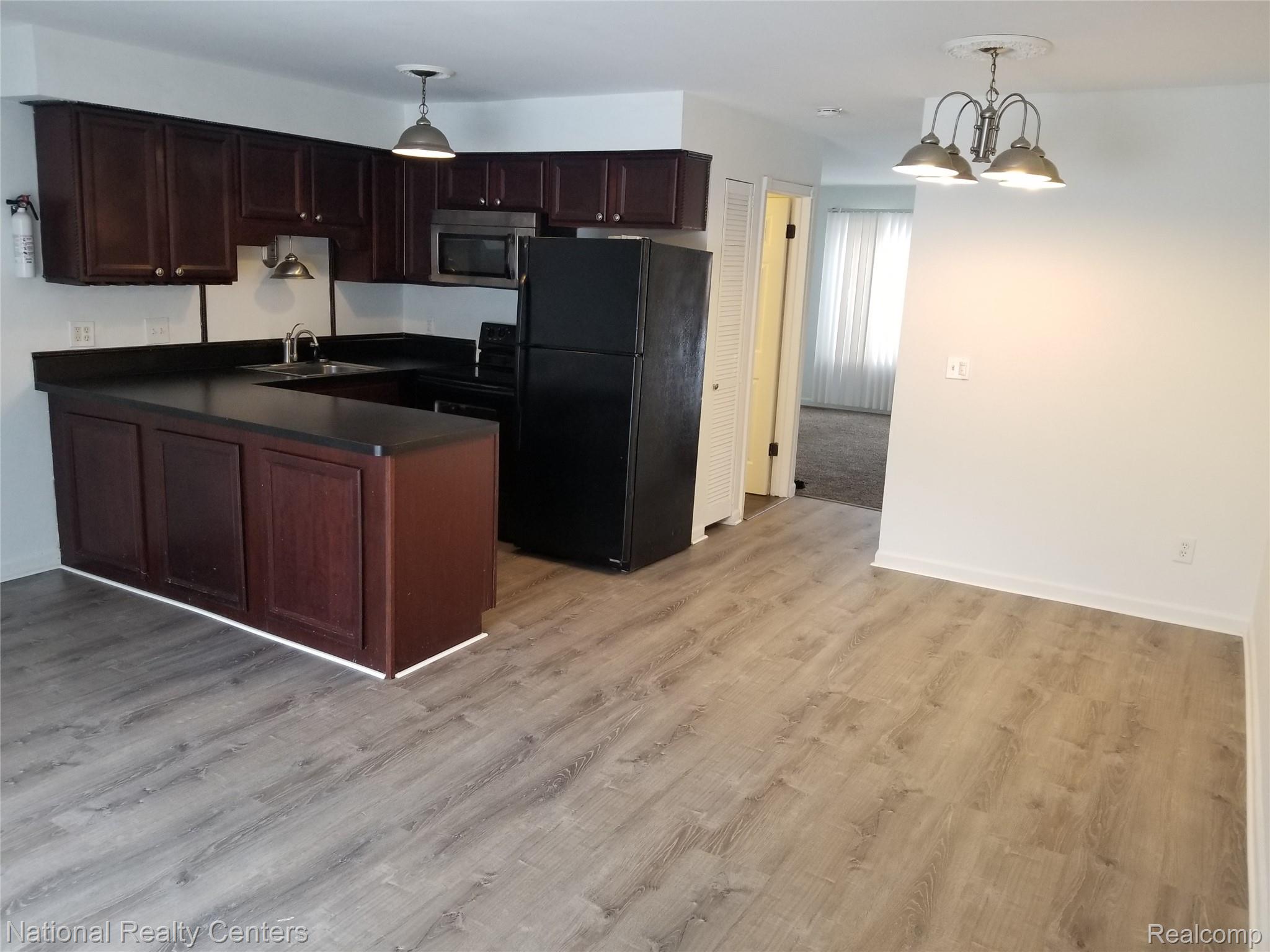 15175 Raphael Terrace Warren, MI 48088 - Photo 9 of 18 Kitchen with wood-finish flooring, dark wood cabinetry, and integrated appliances