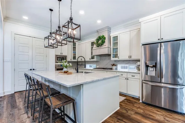 a kitchen with stainless steel appliances granite countertop a sink a stove a refrigerator and island