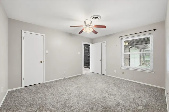 a view of an empty room with chandelier fan