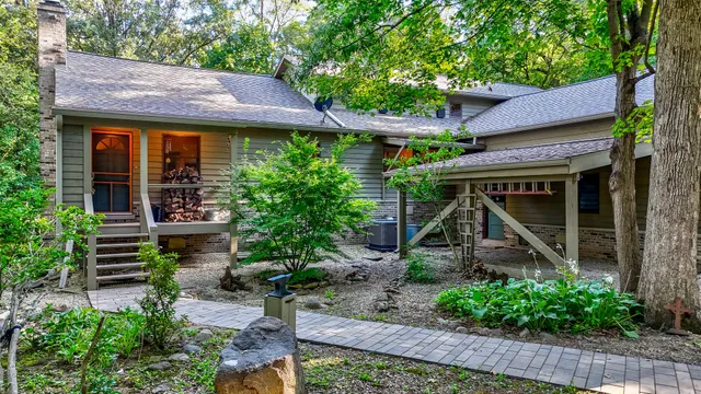 a view of a house with a yard plants and large tree