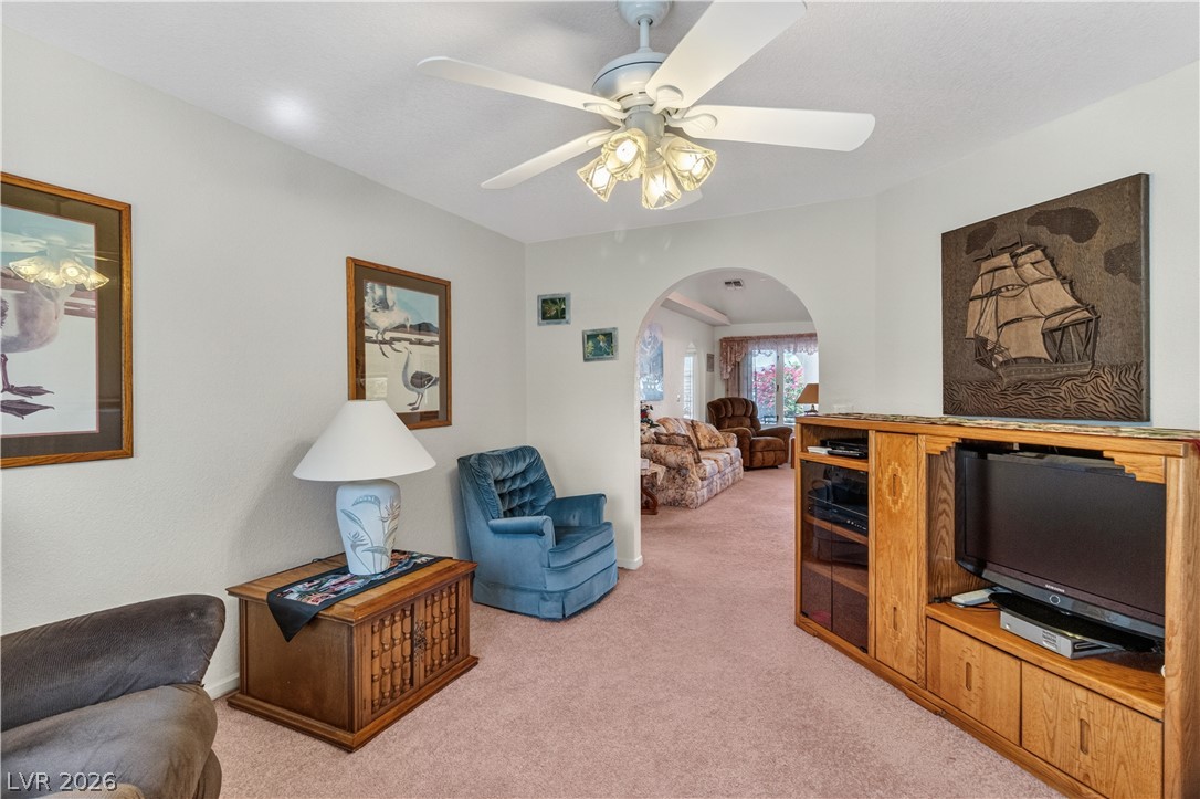 2055 Cholla Way Laughlin, NV 89029 - Photo 11 of 87 An inviting common area features a ceiling fan, plush carpeting, and an arched entryway to additional living space.