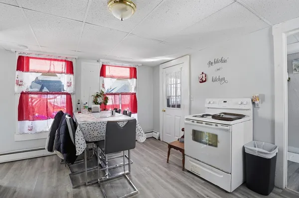 a kitchen with a stove a refrigerator and a dining table with wooden floor