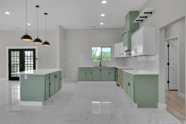 a kitchen with kitchen island cabinets a sink a window and stainless steel appliances