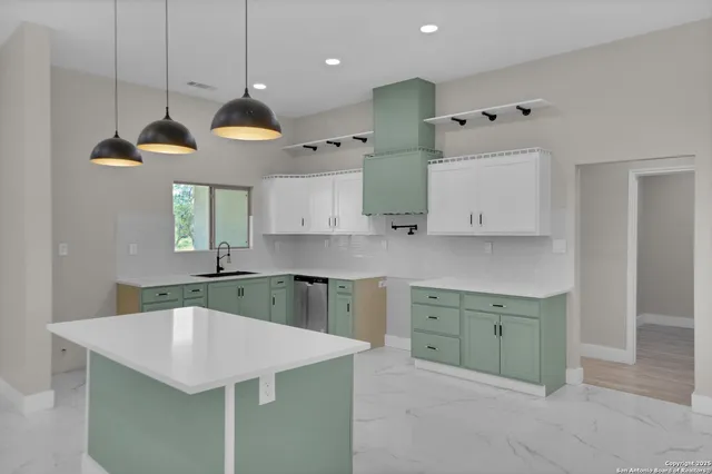 a kitchen with a stove a sink a center island a counter top space and cabinets