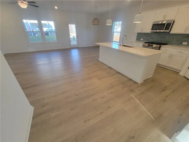 a large white kitchen with kitchen island granite countertop a barbecue grill and a sink