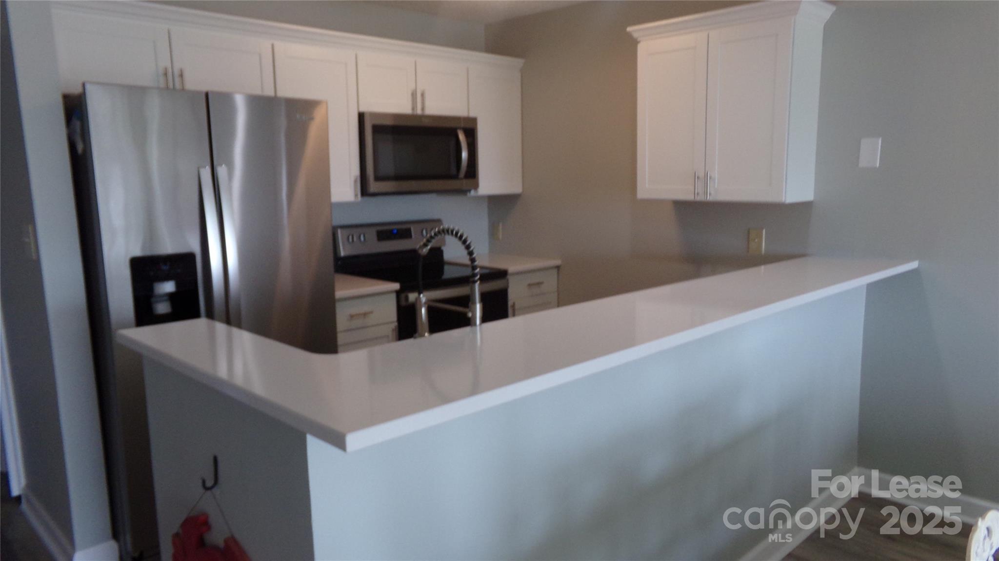17919 Kings Point Drive, Unit E Cornelius, NC 28031 - Photo 6 of 30 a kitchen with stainless steel appliances a refrigerator a stove a sink and white cabinets