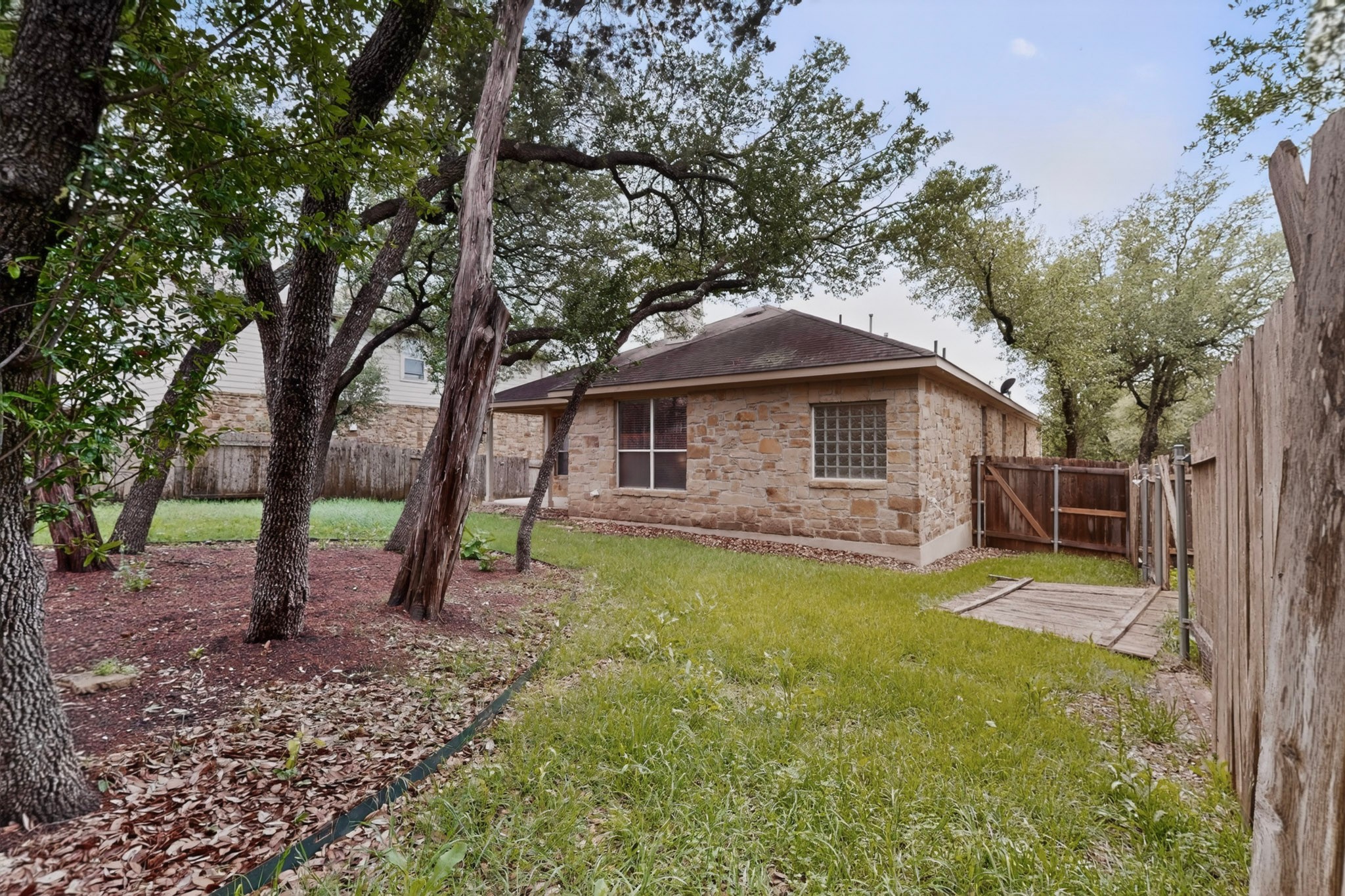 178 Limestone Trail Austin, TX 78737 - Photo 40 of 40 Backyard featuring a stone exterior, mature trees, a covered patio, and a wooden privacy fence