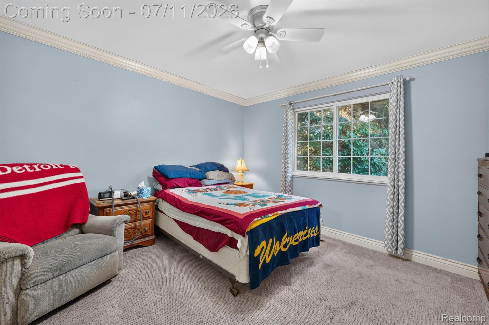 4430 North Center Road Flint, MI 48506 - Photo 23 of 49 Bedroom featuring a ceiling fan with integrated lighting, a window with exterior tree scenery, light blue wall paint, crown molding, and grey carpeting