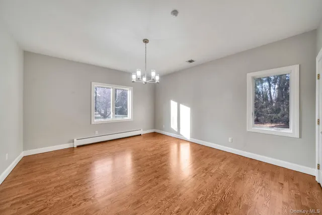 a view of an empty room with chandelier and wooden floor