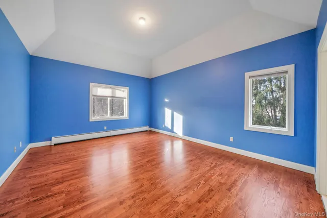 a view of an empty room with window and wooden floor