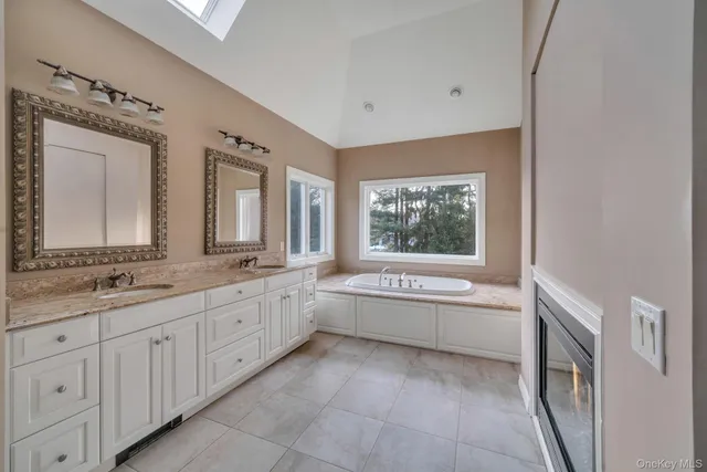 a bathroom with a granite countertop sink a large mirror a bathtub and next to a window