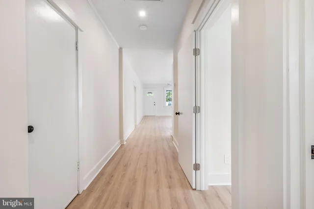 a view of a hallway with wooden floor and a bathroom