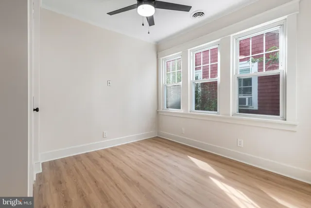 a view of empty room with wooden floor and fan
