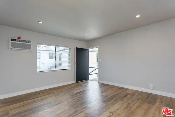 a view of an empty room with wooden floor and a window