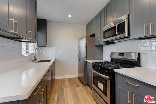a kitchen with stainless steel appliances a stove a microwave a sink and cabinets