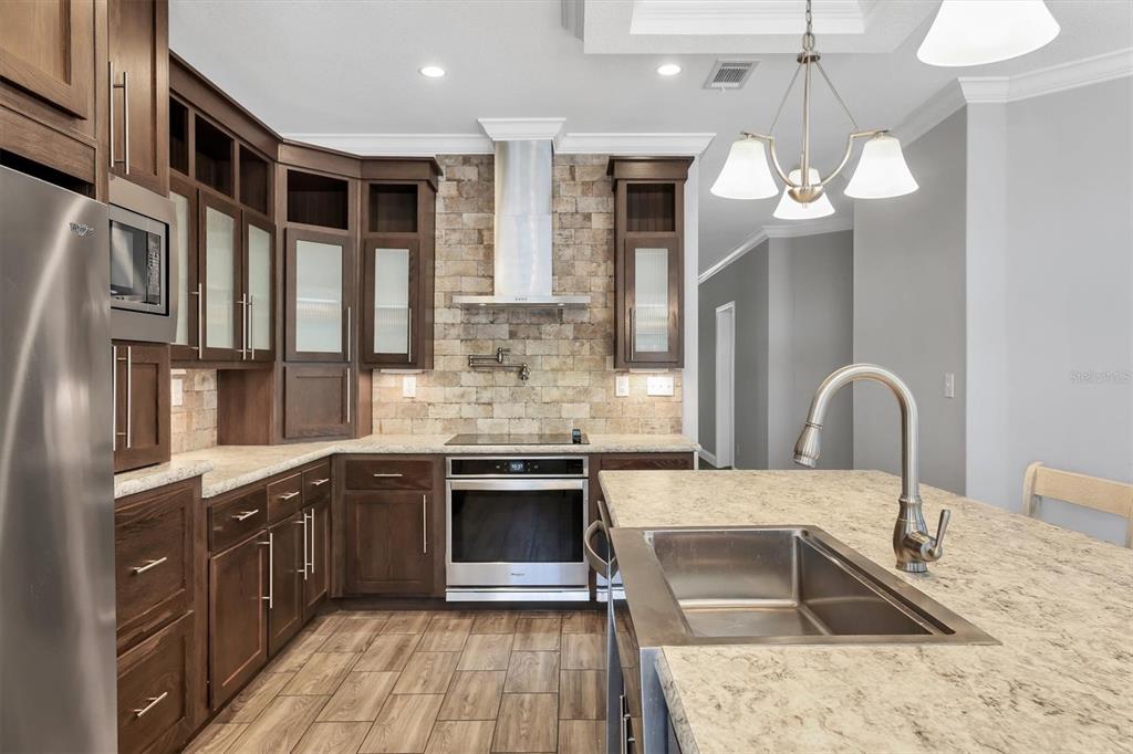 3607 70th Avenue East Ellenton, FL 34222 - Photo 12 of 43 a kitchen with stainless steel appliances granite countertop a sink and a stove top oven with wooden floor