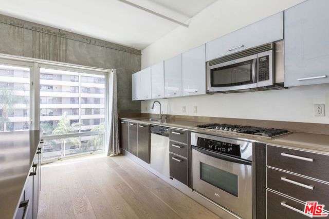 a kitchen with stainless steel appliances a stove microwave and sink