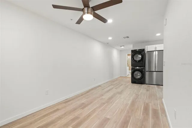 an empty room with wooden floor chandelier fan and windows