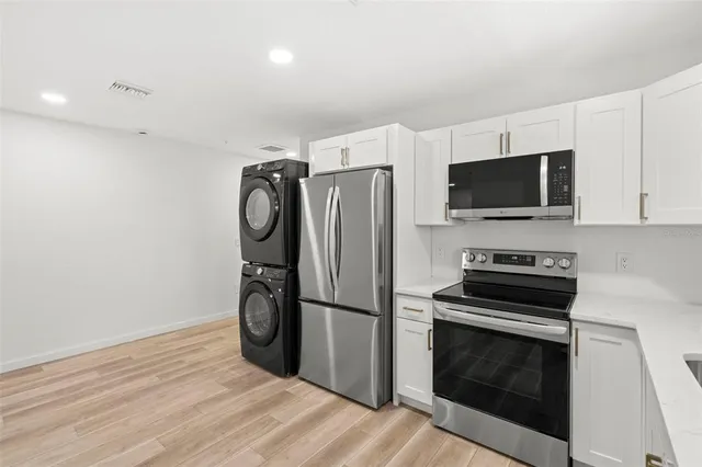 a kitchen with a refrigerator a sink dishwasher a stove and white cabinets with wooden floor